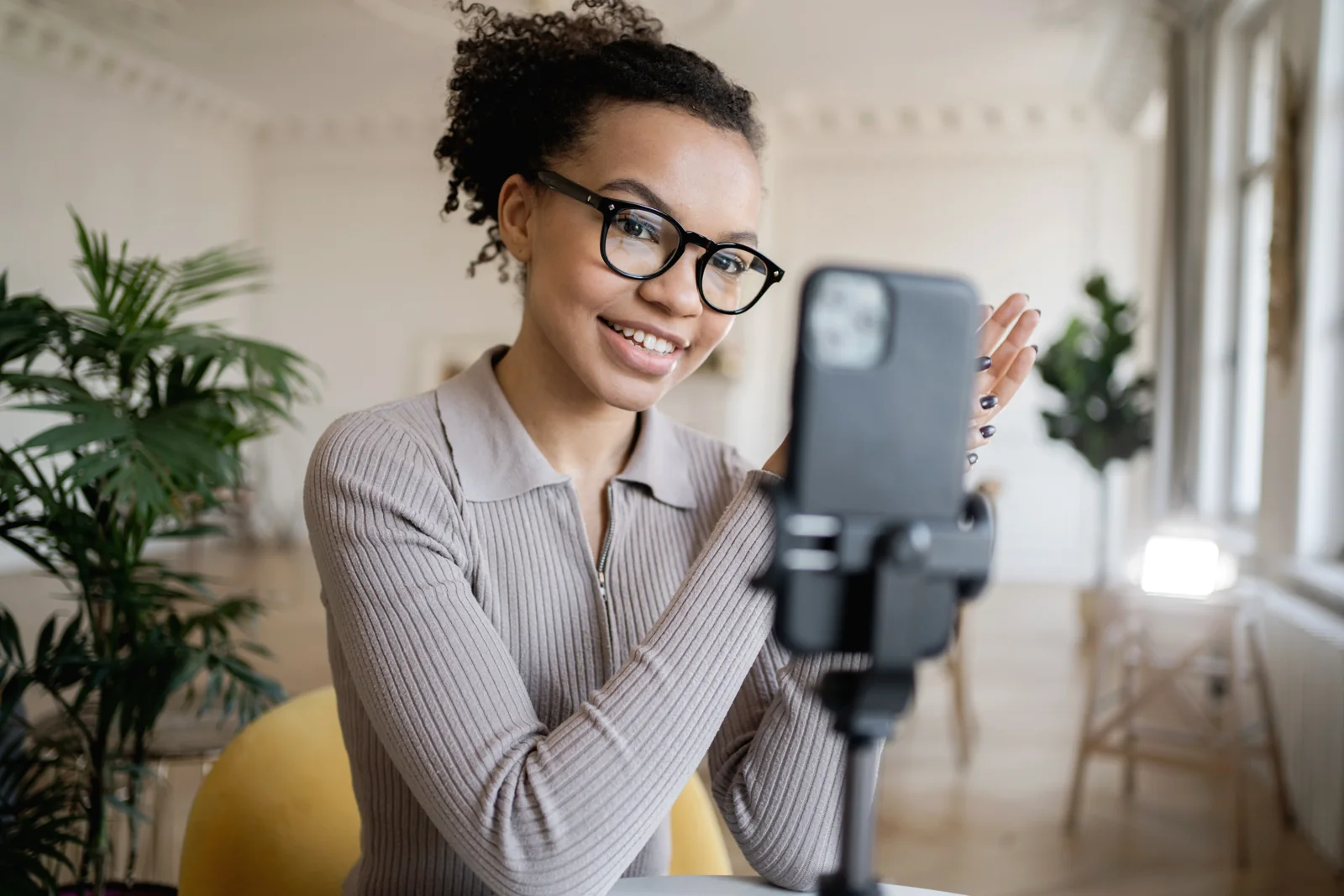 A smiling creator records a video on her phone